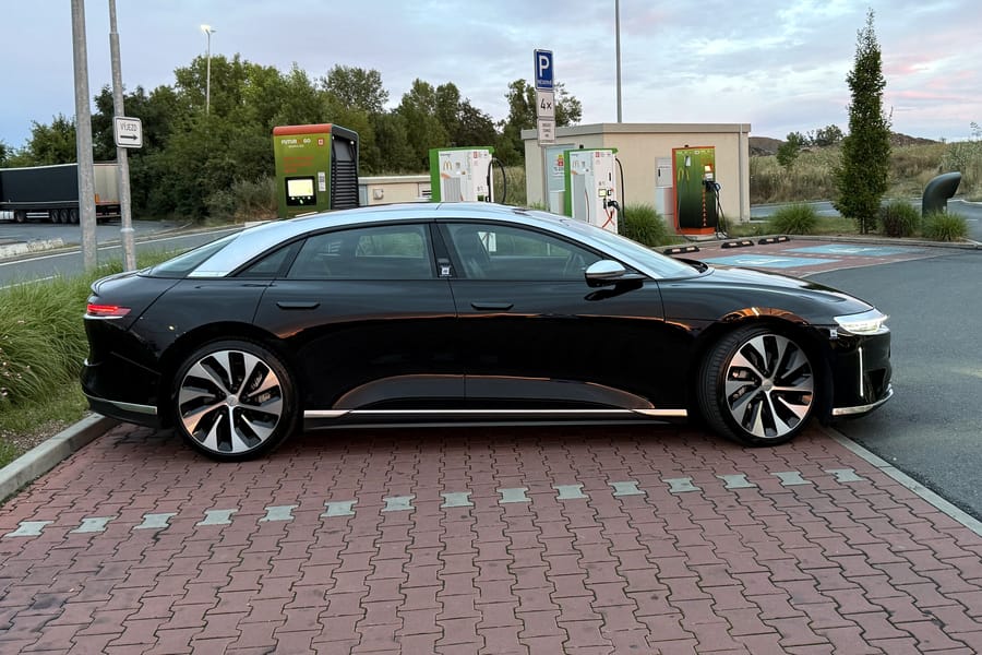 Lucid Air Grand Touring z boku na parkovišti s nabíječkami, Praha, večer