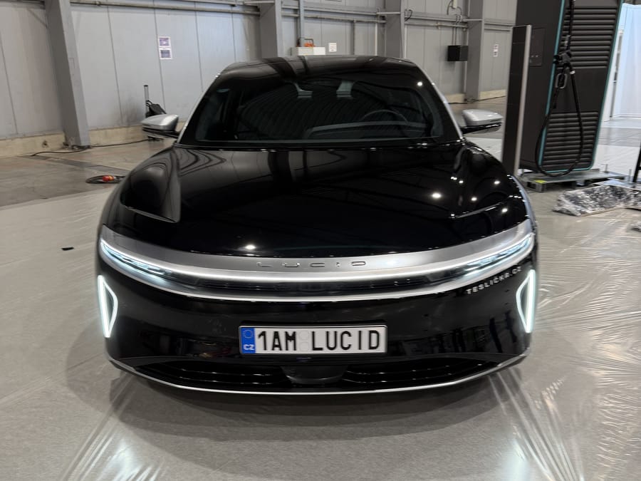 Lucid Air Grand Touring zepředu s rozsvícenými světly v hale